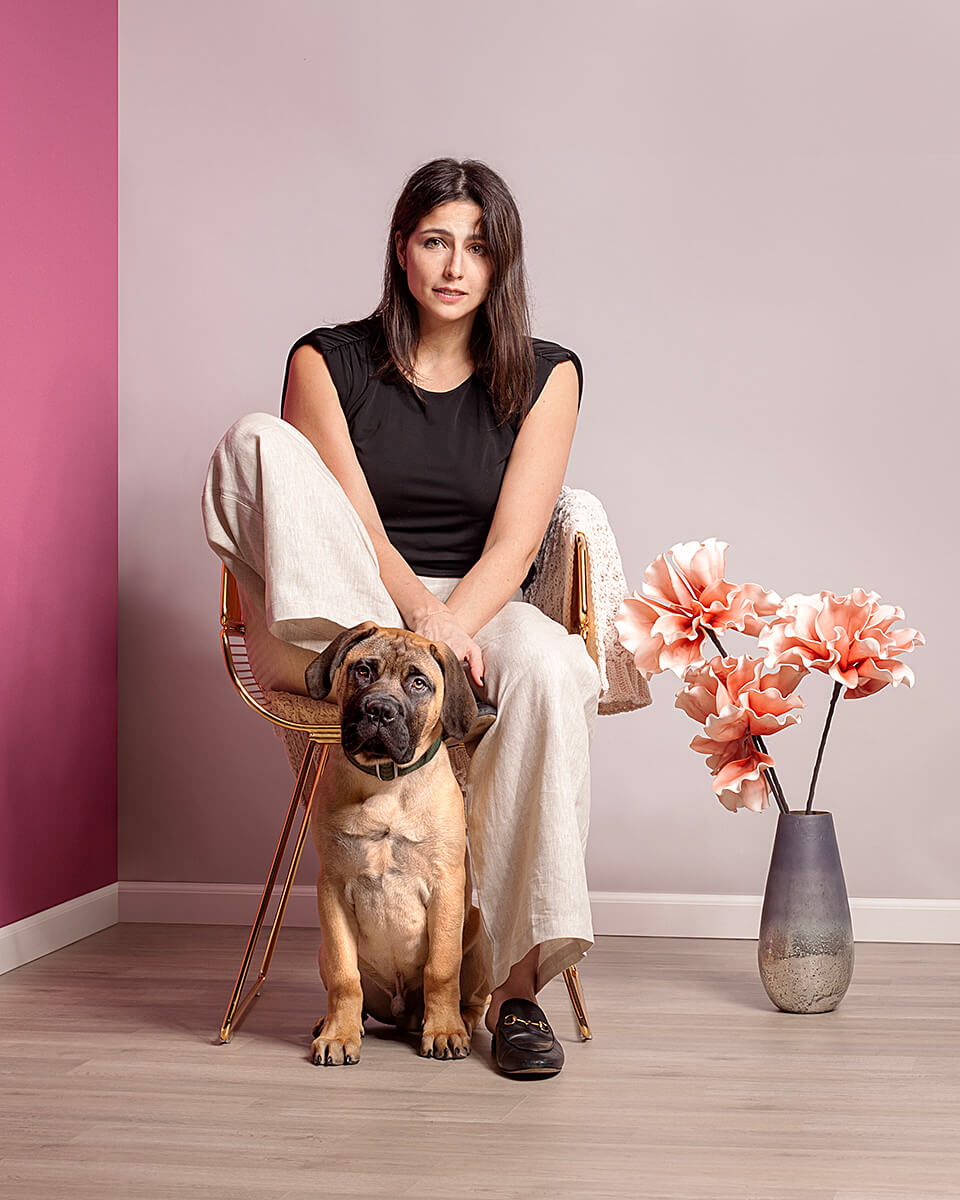 Fashionable woman in a chic setting, casually posed with a lovable bulldog puppy.